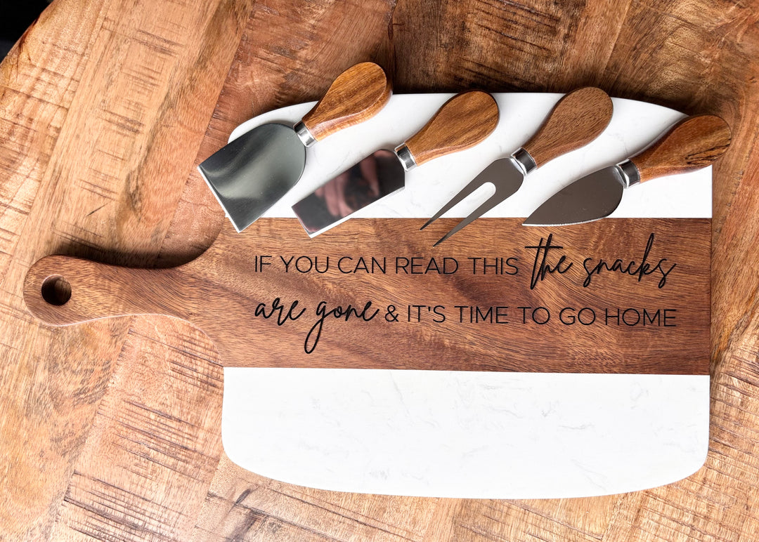 Close-up of custom logo engraving on marble and acacia charcuterie board with knife set