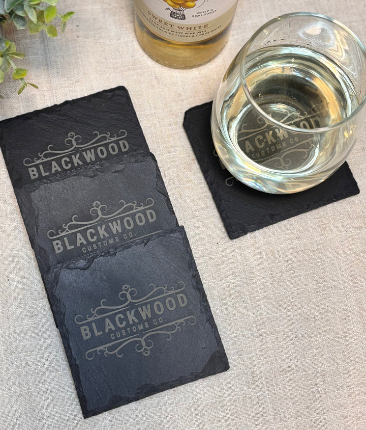 Custom engraved slate coasters on table for business or closing gift
