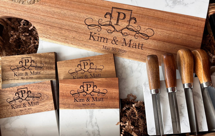 Close up of personalized charcuterie board with engraved names matching coasters and cheese knives custom wedding and closing gift set