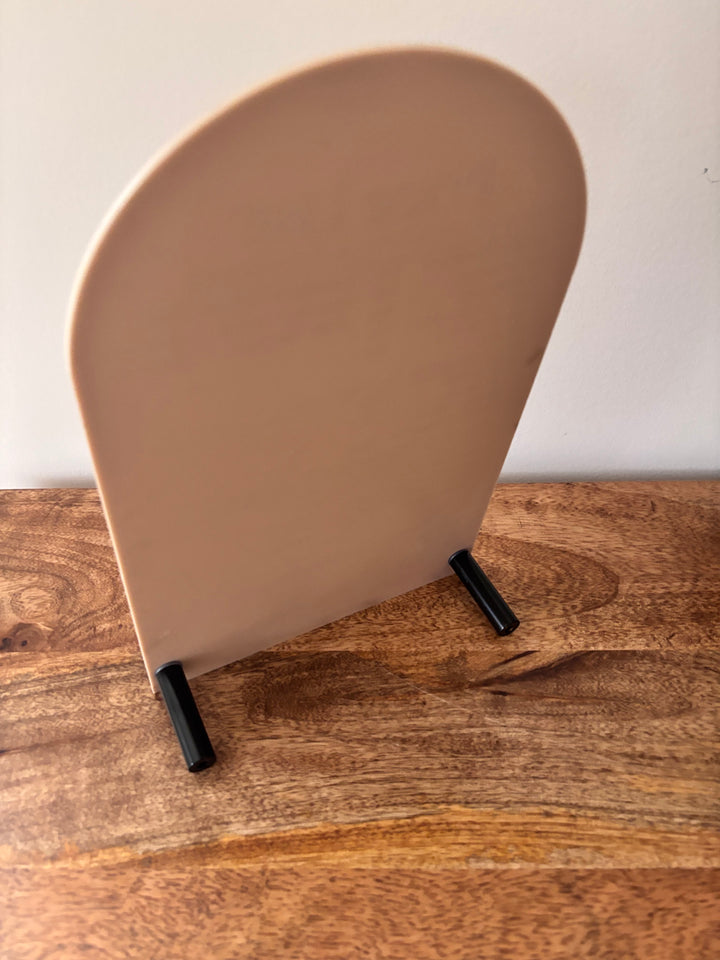 Arched frosted acrylic sign blank with two black peg stands, displayed on a wooden surface for custom laser engraving or vinyl lettering.
