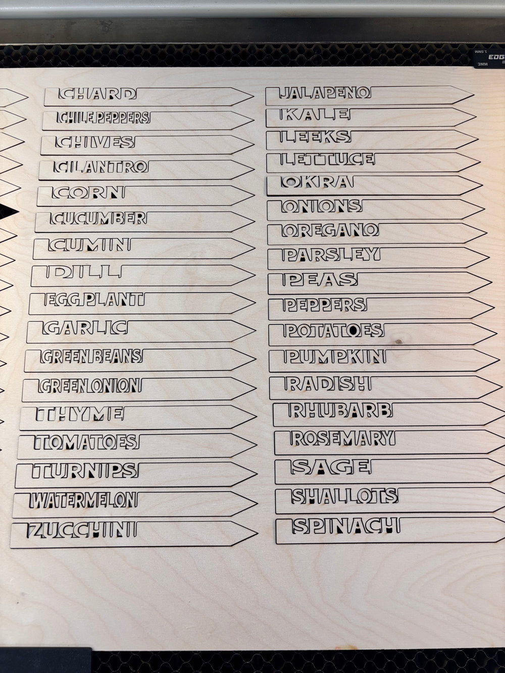 laser cut wooden garden marker stakes with vegetable and herb names on a wood sheet ready for planting labels