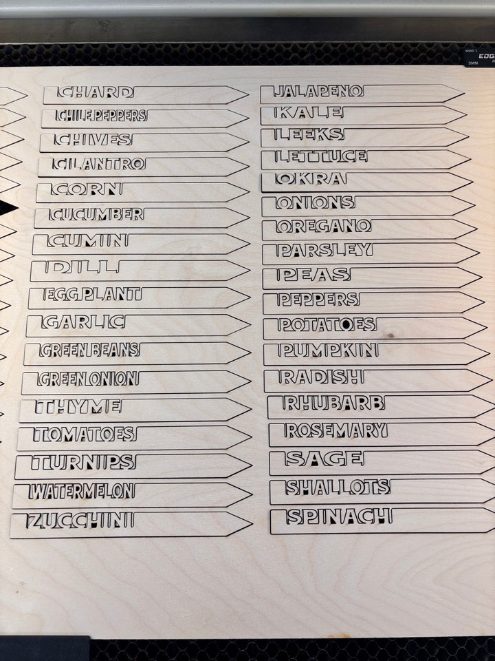 laser cut wooden garden marker stakes with vegetable and herb names on a wood sheet ready for planting labels