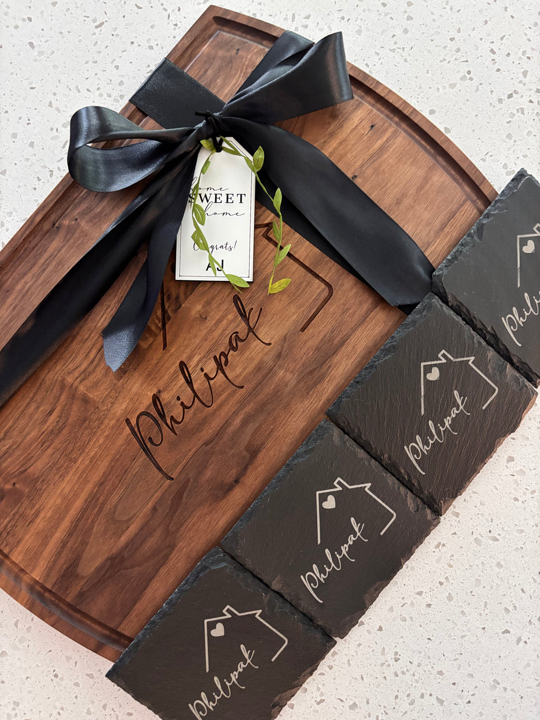 Engraved wooden cutting board and slate coaster set styled as housewarming realtor client gift basket
