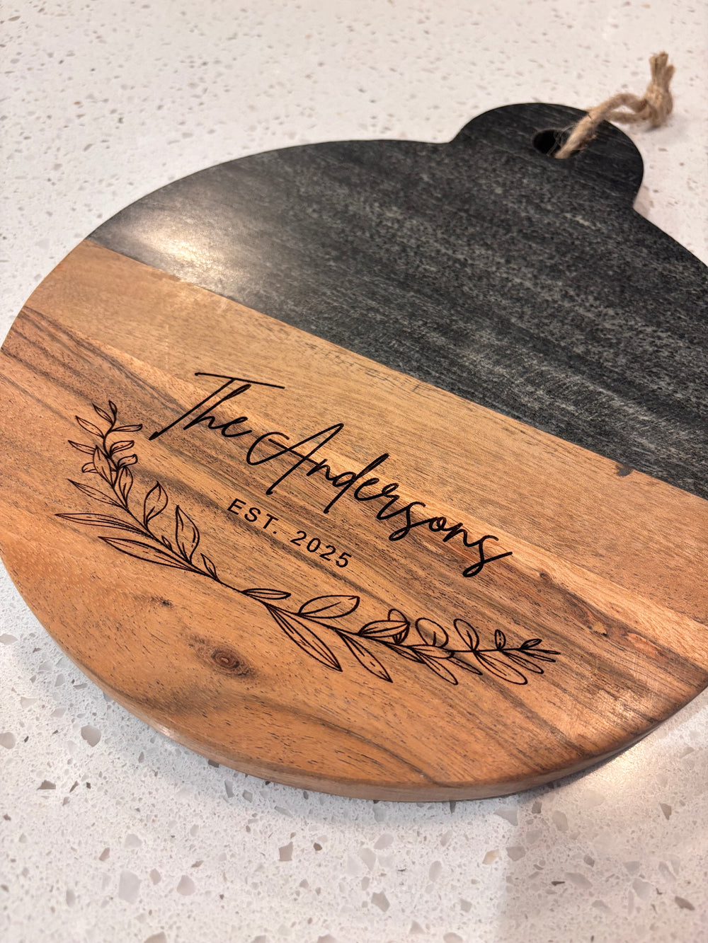 Personalized marble and wood round cutting board engraved with family name and established date, perfect wedding or housewarming gift.