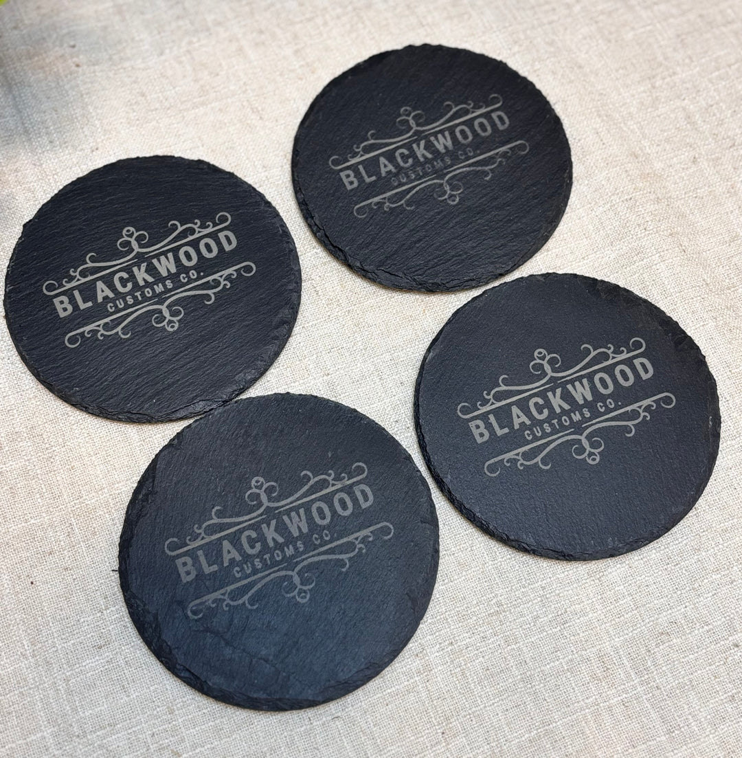 Set of four custom slate coasters with engraved branding for corporate gifts

