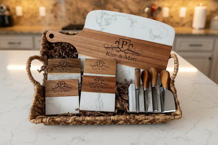 Personalized wedding and closing gift basket with engraved marble and acacia charcuterie board cheese knives and matching coasters displayed on kitchen counter