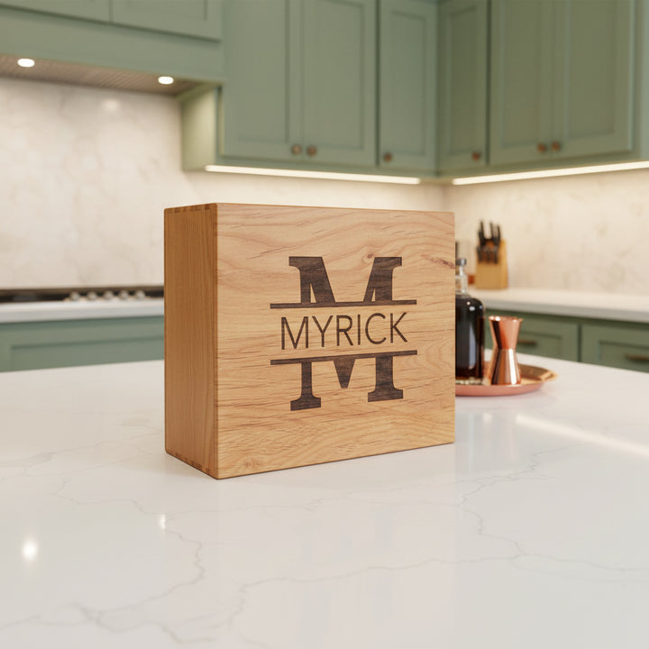 Personalized engraved wooden whiskey gift box with monogram initial and name on lid displayed on kitchen counter for groomsmen wedding and corporate gifts