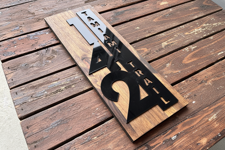 Custom wooden address sign with house numbers and vertical street name mounted beside a front door entrance